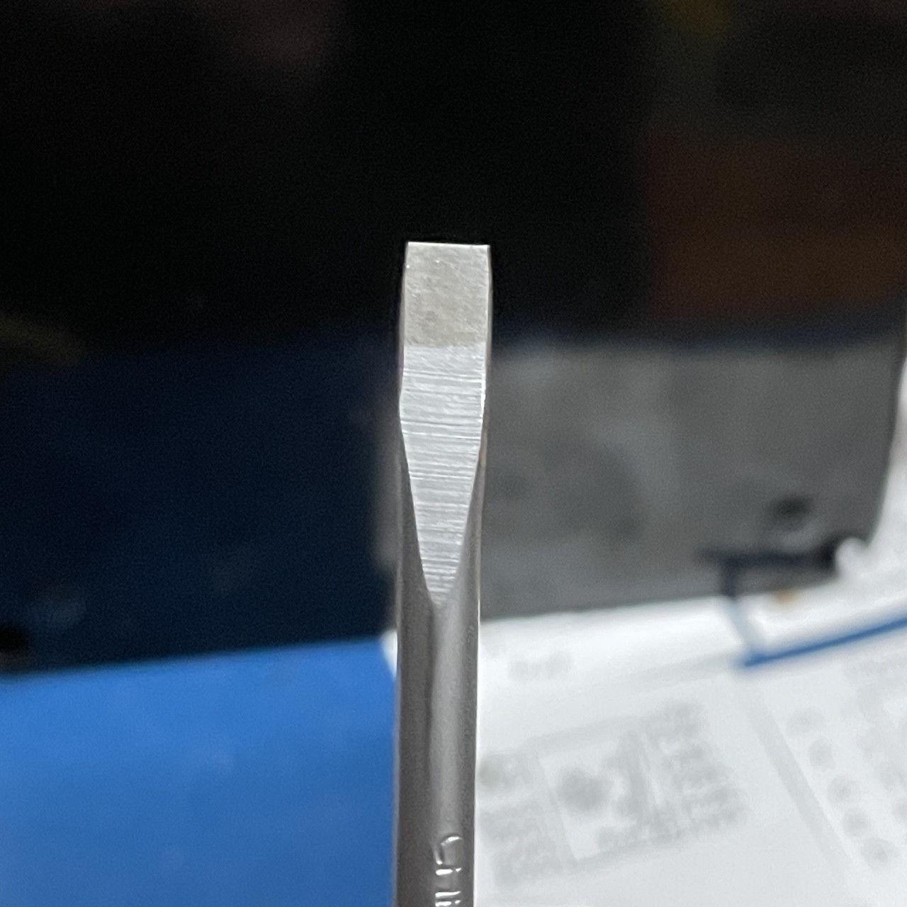 A flat blade screwdriver head. The sides have been filed down so it’s only as wide as the shaft.