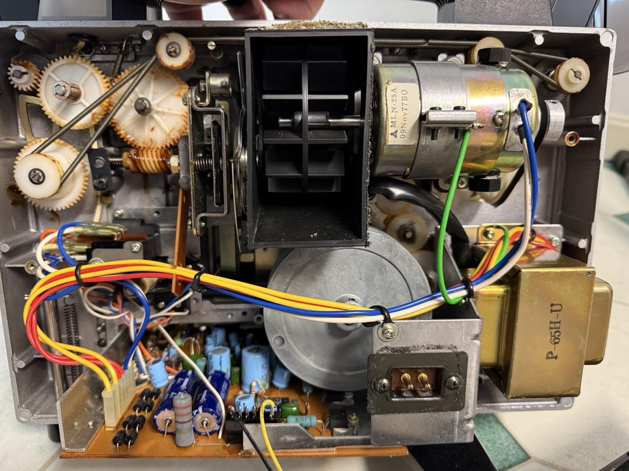 The interior of a GAF 3100S Super 8 projector showing gears, wires, circuit boards, etc.